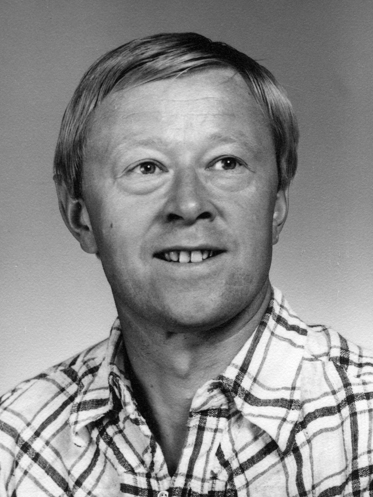 1970s black and white portrait of blond man, Karl Kerker, in check shirt.