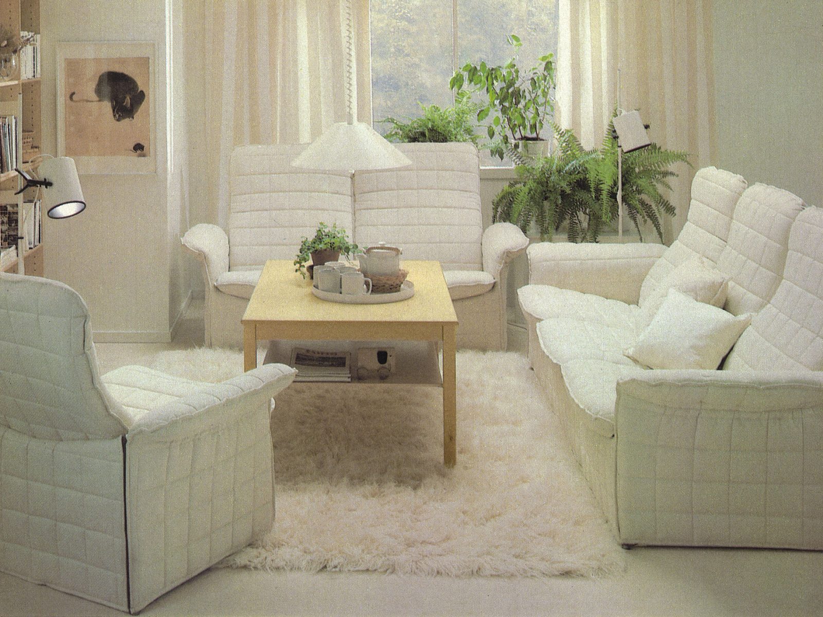 Ljus interiörbild från IKEA katalogen, vit fåtölj och soffa, TULLANÄS, står på vit ryamatta.