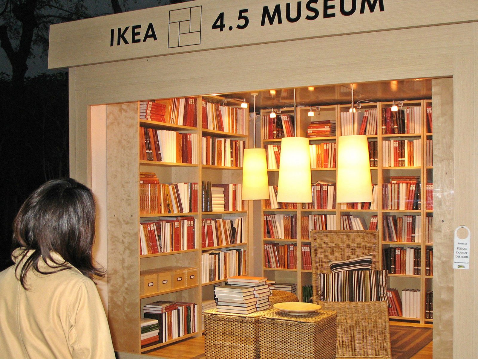 Uppbyggd rumsinteriör i trä, med bokhyllor längs väggarna och små korgmöbler. Text vid ingången lyder IKEA 4,5 MUSEUM.