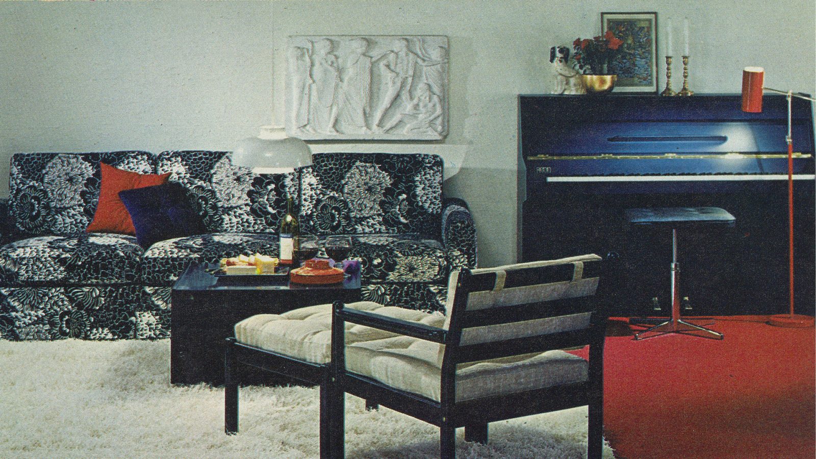 1970-talsinteriör med svartvita möbler, vit ryamatta och mörkblått piano.