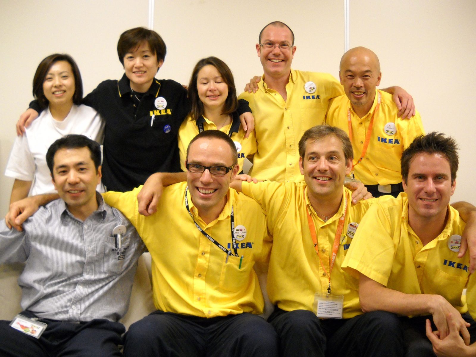 Group photo of seated happy people in IKEA staff uniforms.