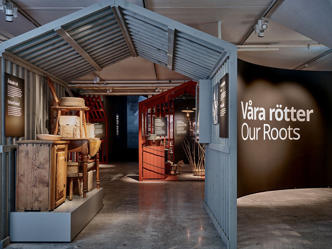 A house-like blue shape with wooden furniture from the era in which IKEA was founded, and “Our Roots” written on a wall.
