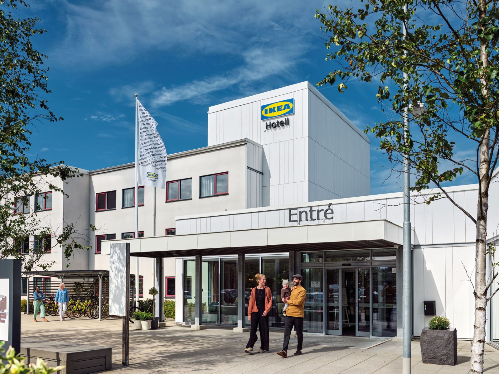 A casually dressed couple comes out of a white building that has a sign with the text IKEA Hotell.