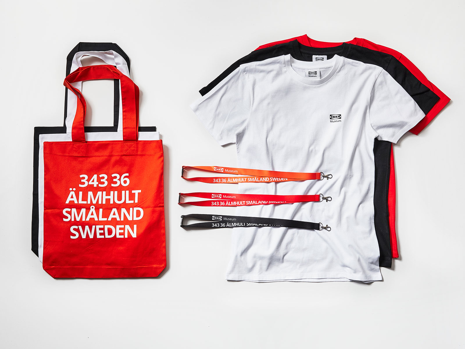 T-shirts, key chains and tote bags in red, orange or black with text saying: 343 36 ÄLMHULT SMÅLAND SWEDEN.