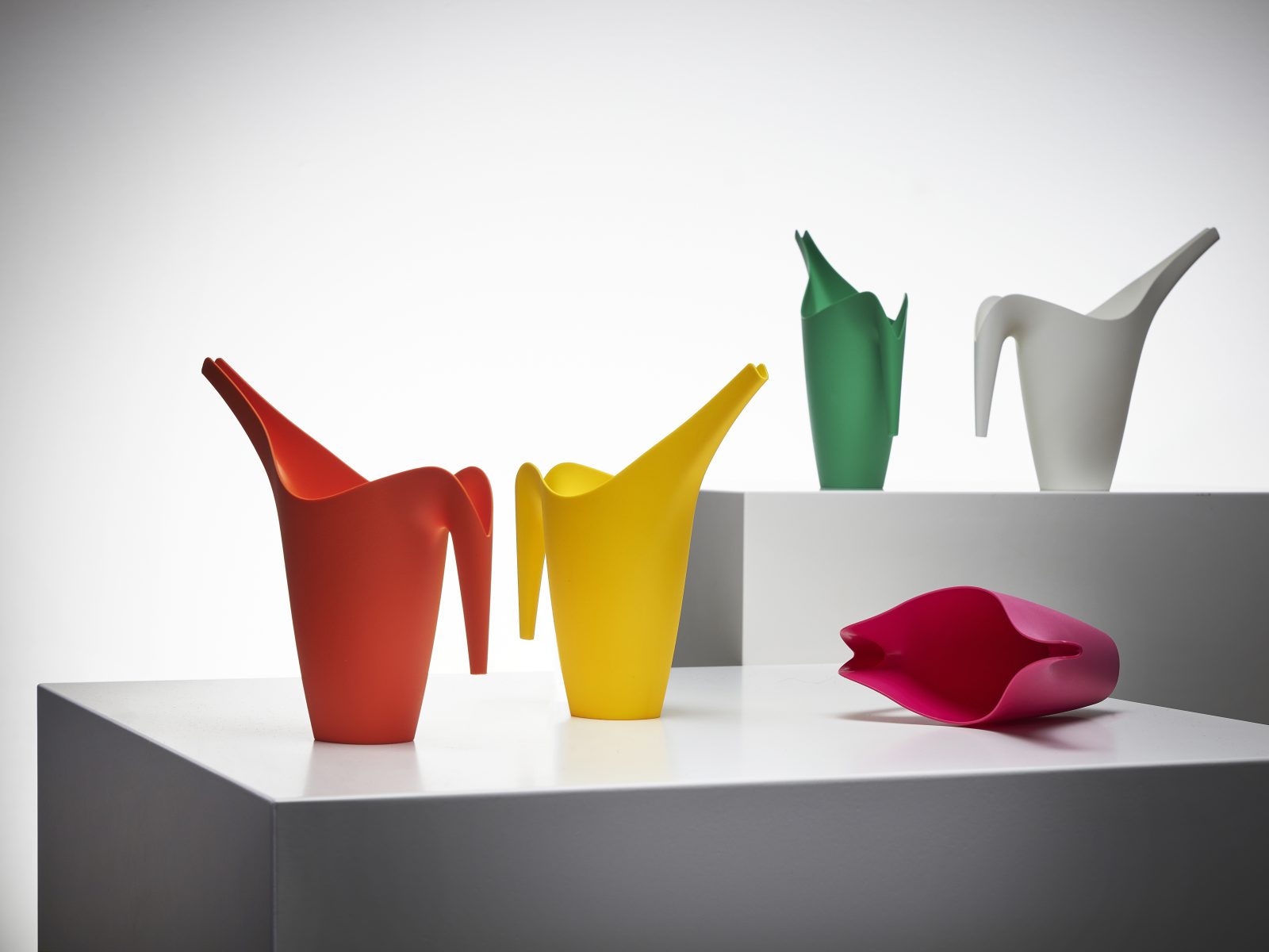 Watering can in five different colours. White, pink, red, green and yellow.