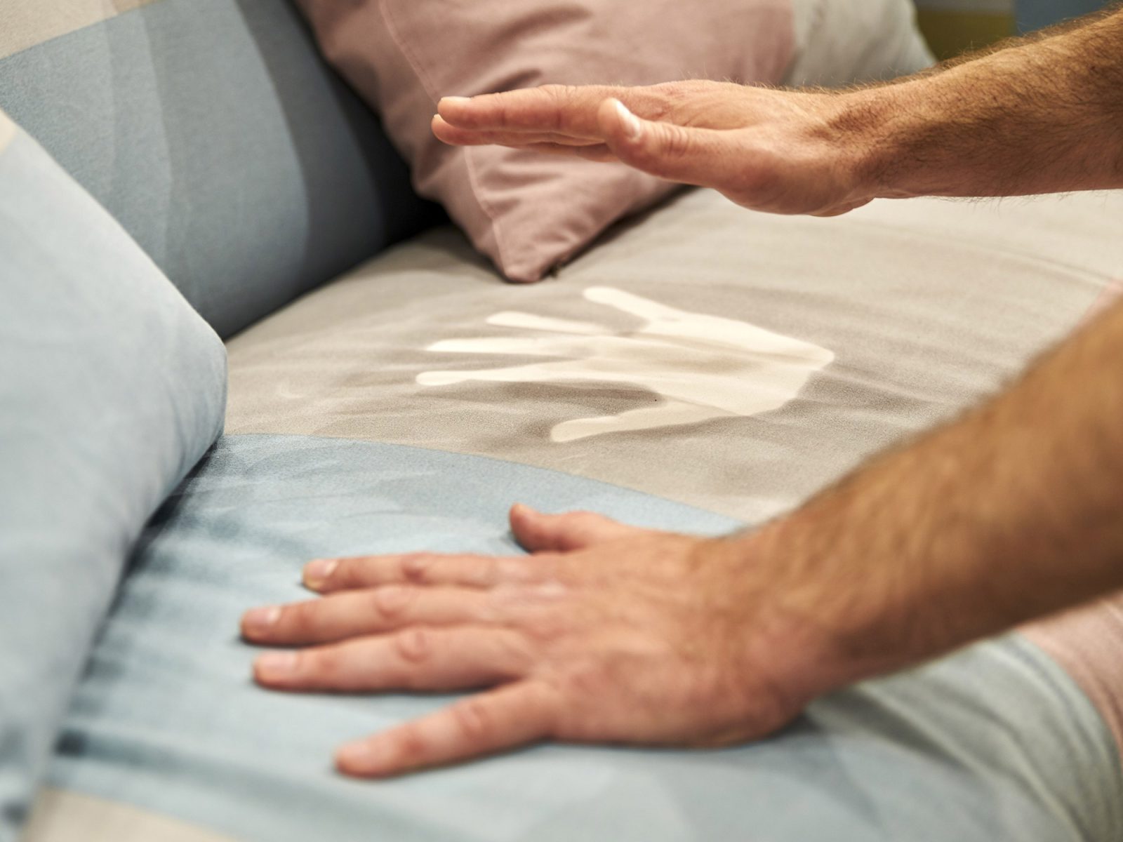 Person places hands on a sofa that changes colour based on their body heat from blue to white.