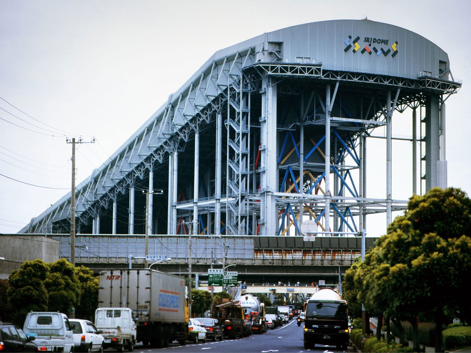 Huge steel construction with the text Ski Dome on the end, a busy highway visible in the foreground.