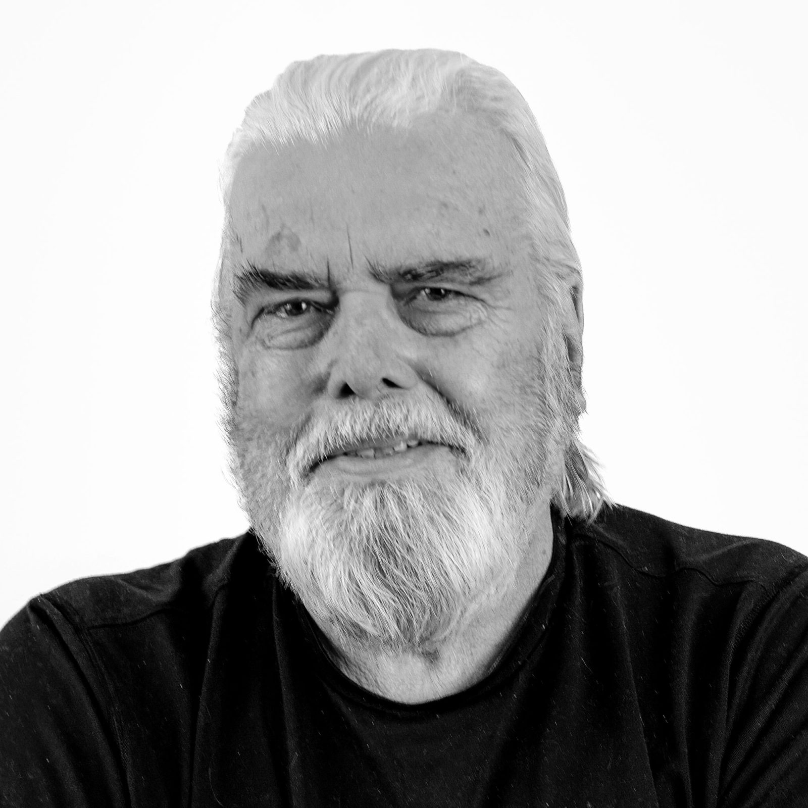 A white-haired older man, Hans Merving, with greying beard and black sweater.
