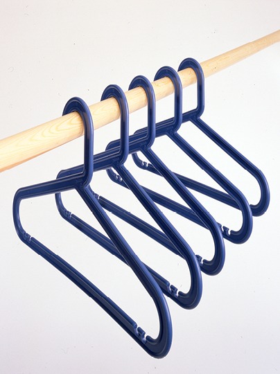 Dark blue plastic coat hangers hanging on a wooden clothes rail.