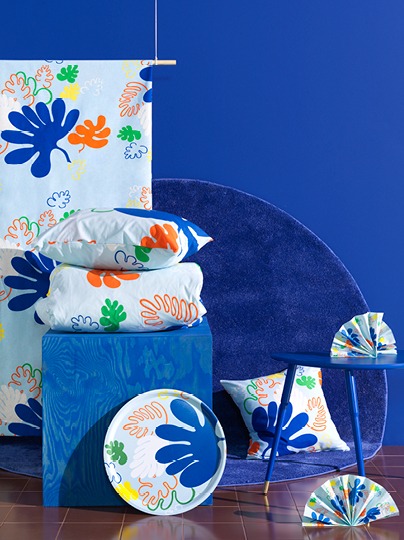 Textile and home furnishing products using a bright-coloured and irregular leaf pattern on a sky-blue background.