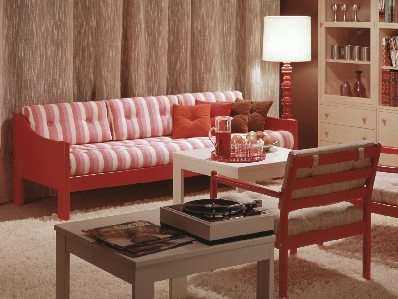Simple red wooden sofa with red and white striped cushions in cosy living room.