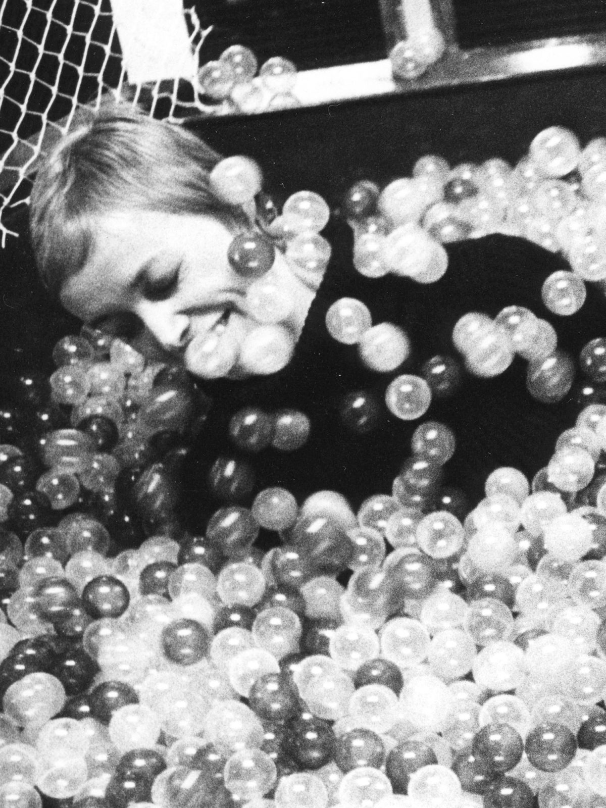 A young woman plays in a ball pit.