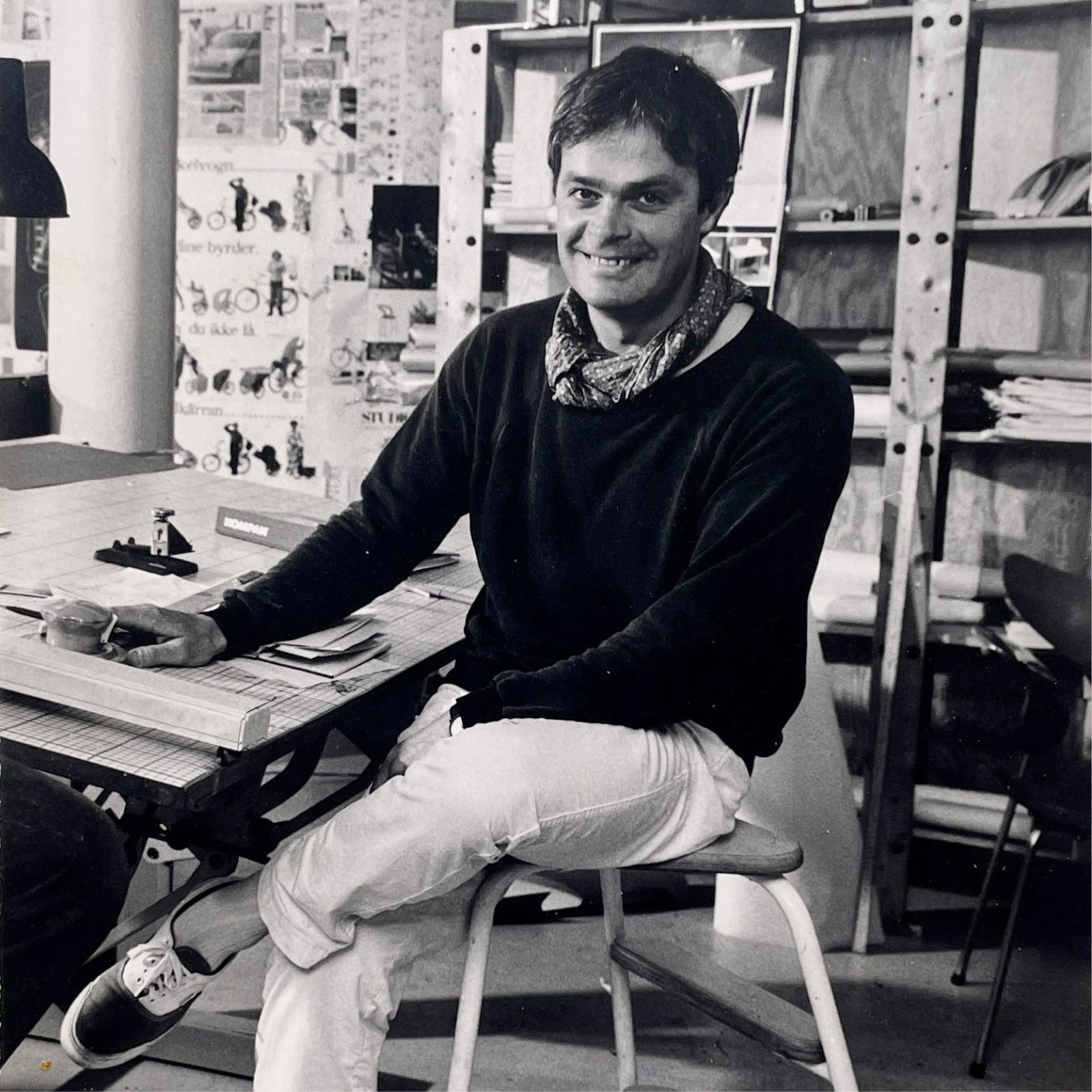 Smiling young man sits at drawing table.