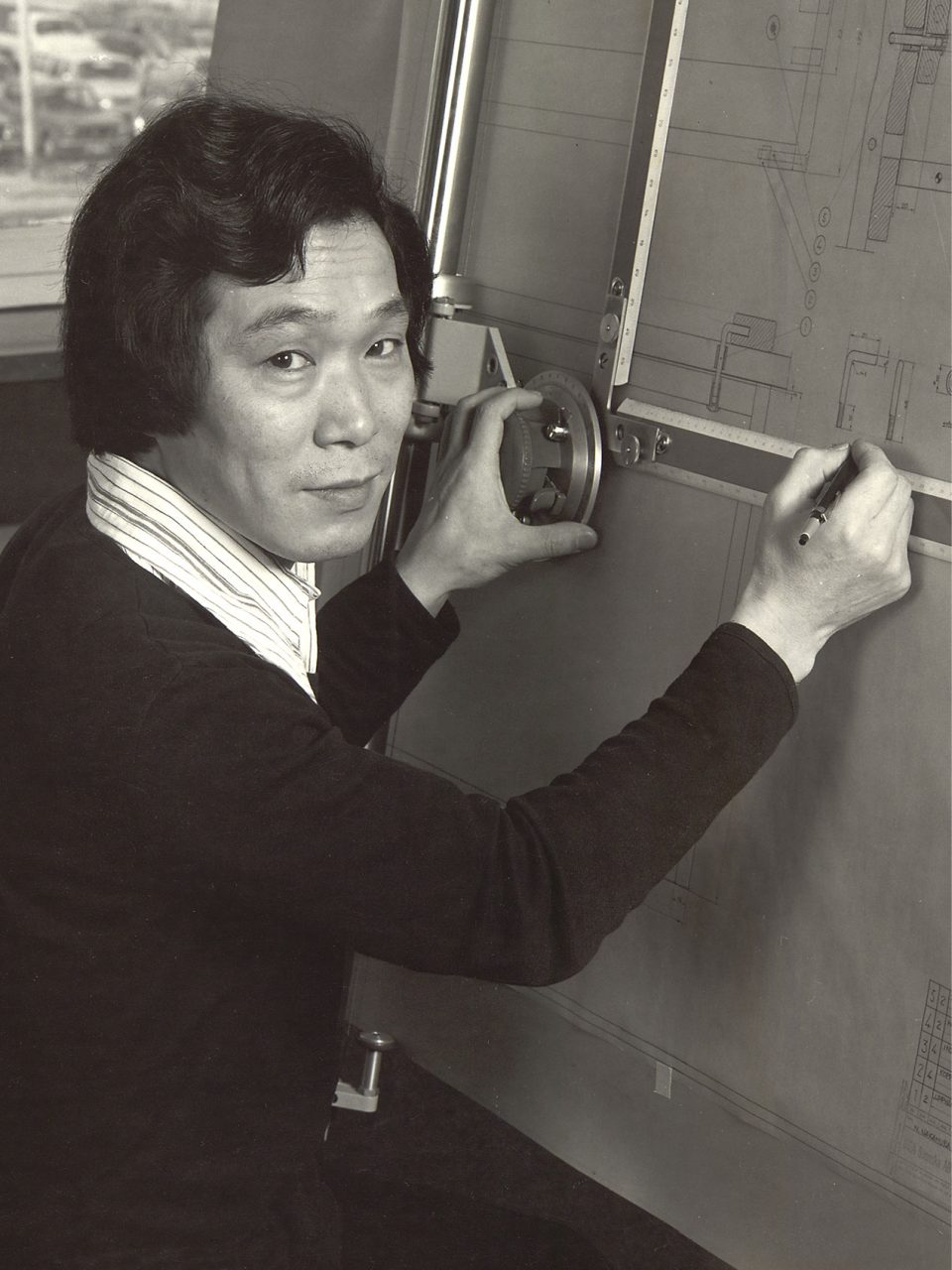 Ung japansk man, Noboru Nakamura, arbetar vid ett ritbord.