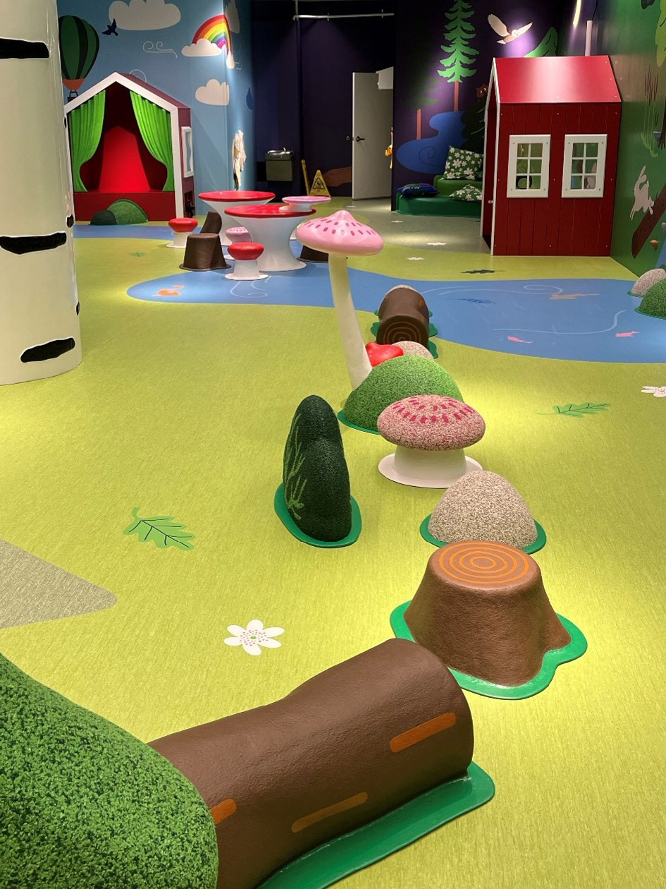 Playroom with green floor, oversized mushrooms and other nature inspired decor.