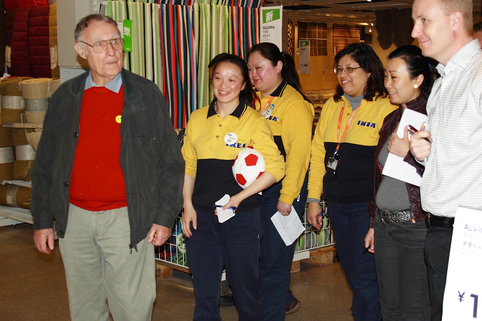Ingvar Kamprad meeting co-workers in an IKEA store, surrounded by staff in yellow uniforms and textiles