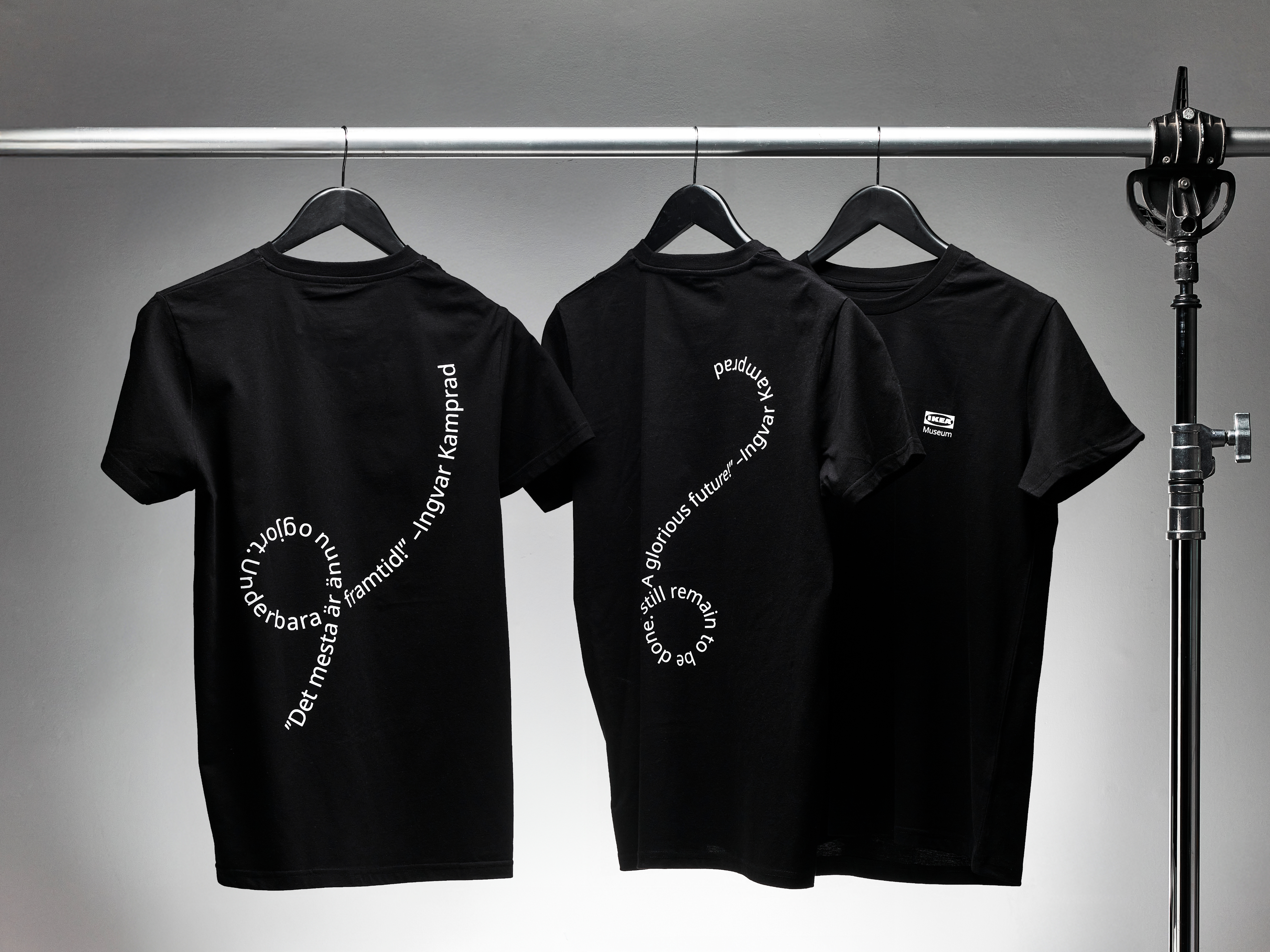 Tre svarta t-shirts med vit vågig text på.