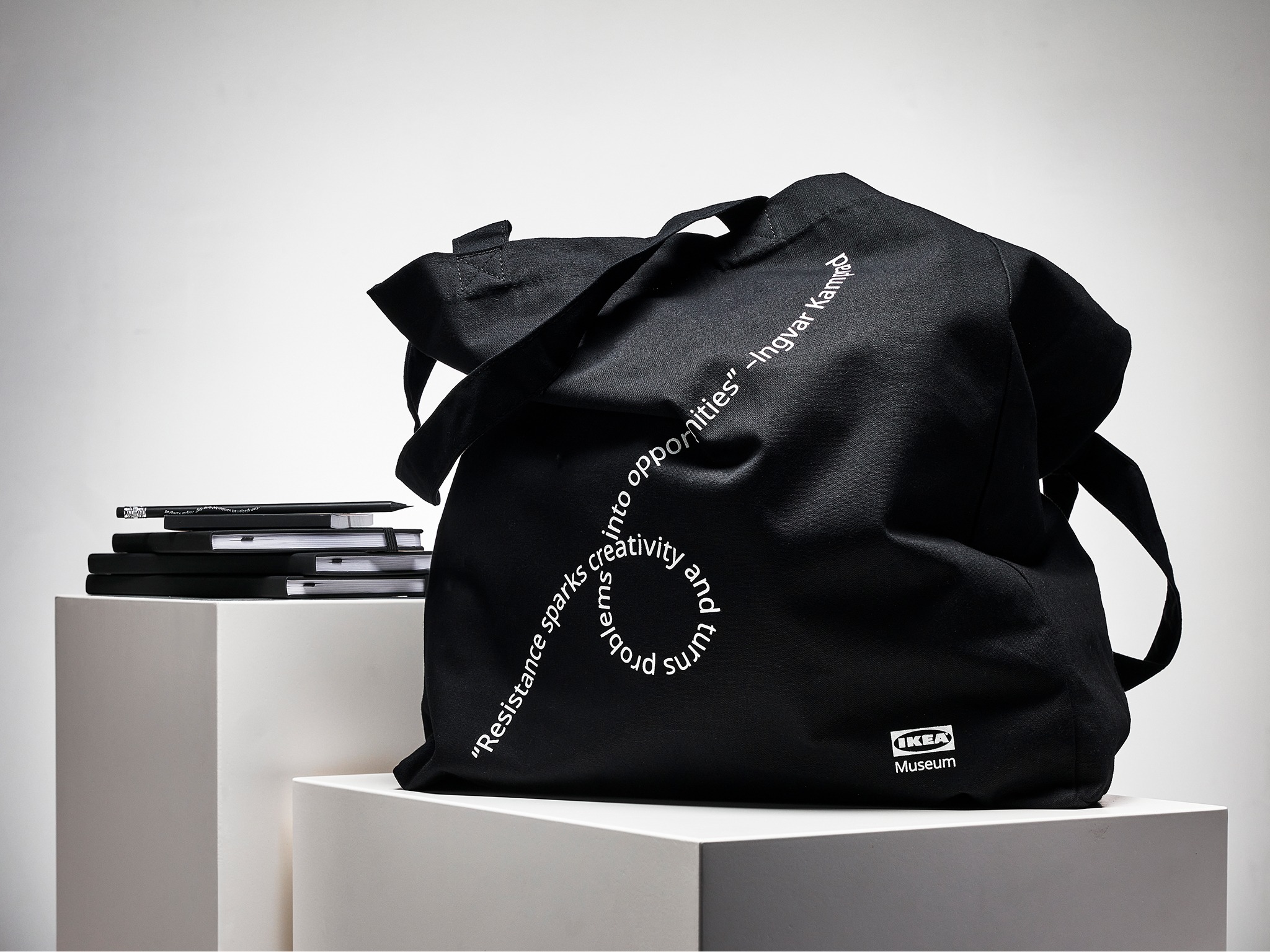 Schwarze Stofftasche mit weißem, wellenförmigem Text.